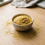 Bol de paillettes de levure de bière dorées sur un plan de travail clair, vue de dessus