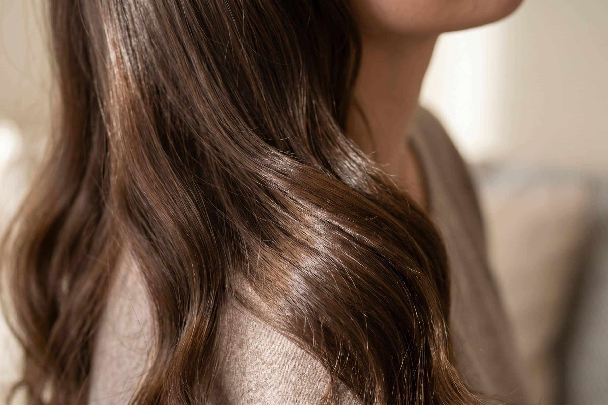 Gros plan sur des cheveux bruns brillants et sains en lumière naturelle