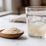 Cuillère de téguments de psyllium blond à côté d'un verre d'eau où le mucilage gonfle